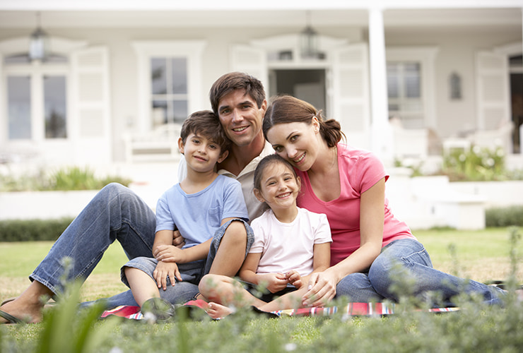 crédito hipotecario fotografía de una familia con dos hijos sentados en el pasto
